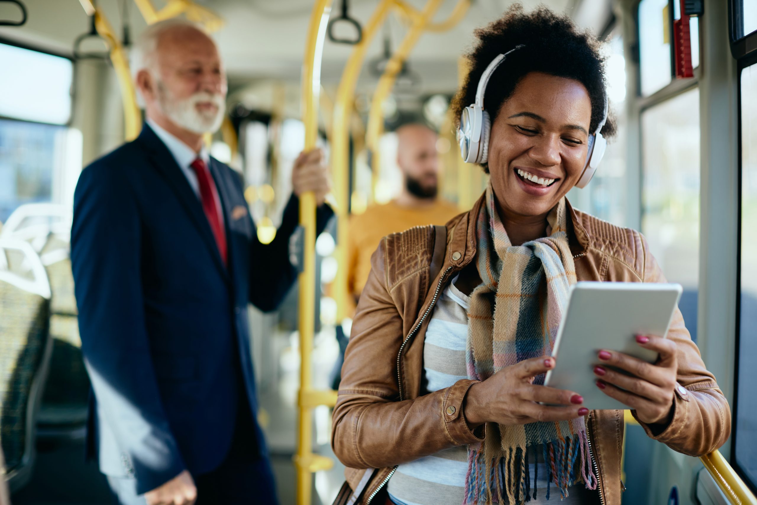 mulher-negra-feliz-com-fones-de-ouvido-com-chamada-de-video-pelo-touchpad-enquanto-se-desloca-de-onibus