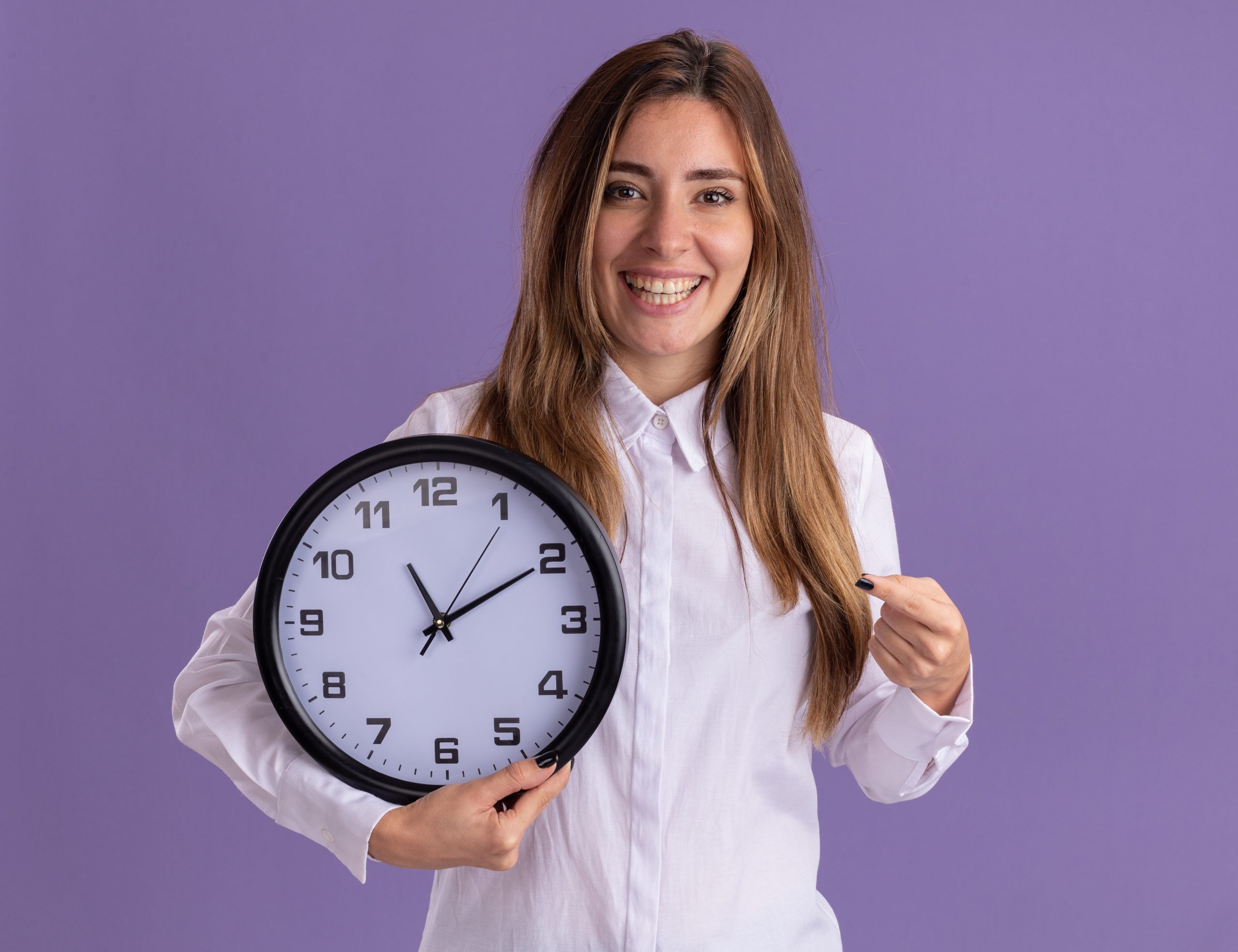 jovem-caucasiana-sorridente-segura-e-aponta-para-um-relogio-roxo
